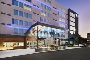 A modern hotel with a glass facade, multiple floors, and a prominent entrance.