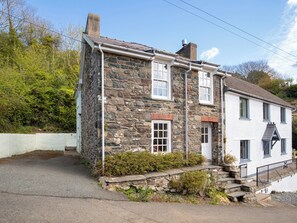 A stone house with a white exterior, a chimney, and a small garden area.