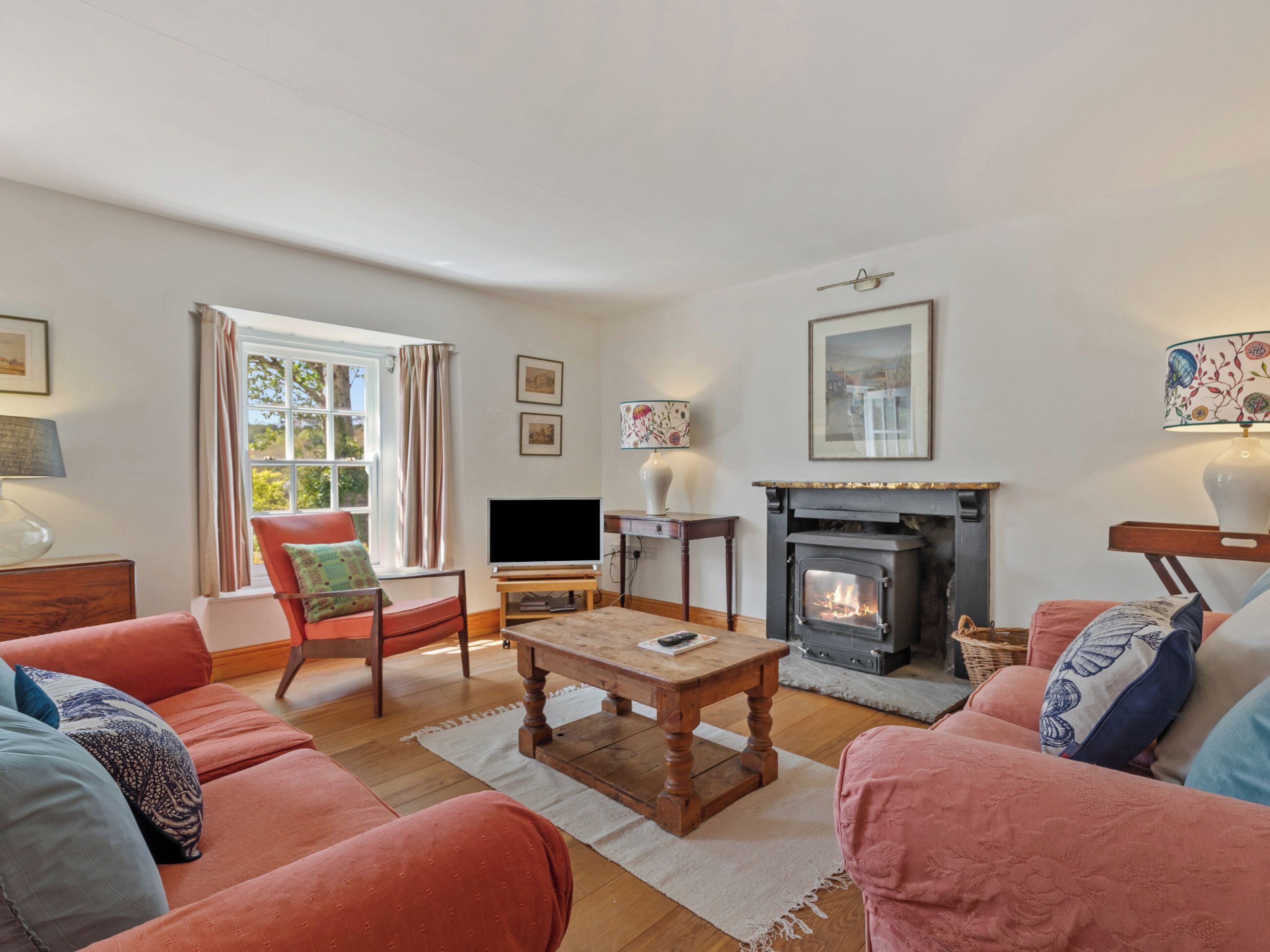 A living room with a fireplace, sofa, television, and a window with curtains.