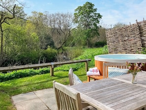 Een houten terras met een jacuzzi, een tafel en stoelen.