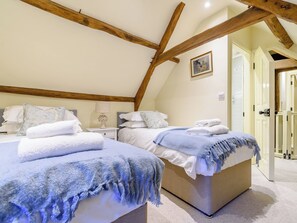 Een slaapkamer met twee bedden, houten balken, een schilderij en een deur.