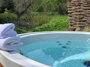 Een hottub met een stapel witte handdoeken, omgeven door groen.