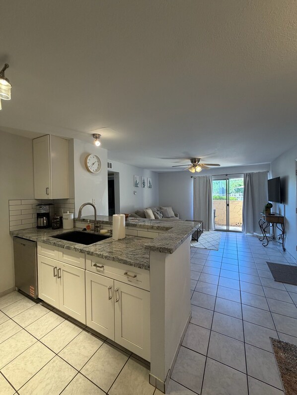 A modern kitchen with a central island, a dining area with a sofa, and a TV mounted on the wall.