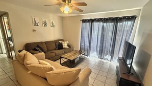 Ein Wohnzimmer mit Sofa, Couchtisch, Fernsehschrank und Deckenventilator.