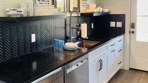 A modern kitchen with black countertops, stainless steel appliances, and a herringbone backsplash. - "Bee Keeper's Cottage" on private estate, new construction, close to everything! (Sarasota)