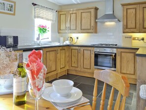 A kitchen with wooden cabinets, a stove, and an oven. There is a window with a view of flowers outside.