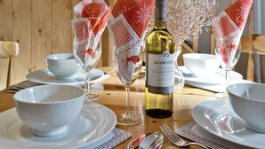 A dining table set with white bowls, wine glasses, and a bottle of wine.