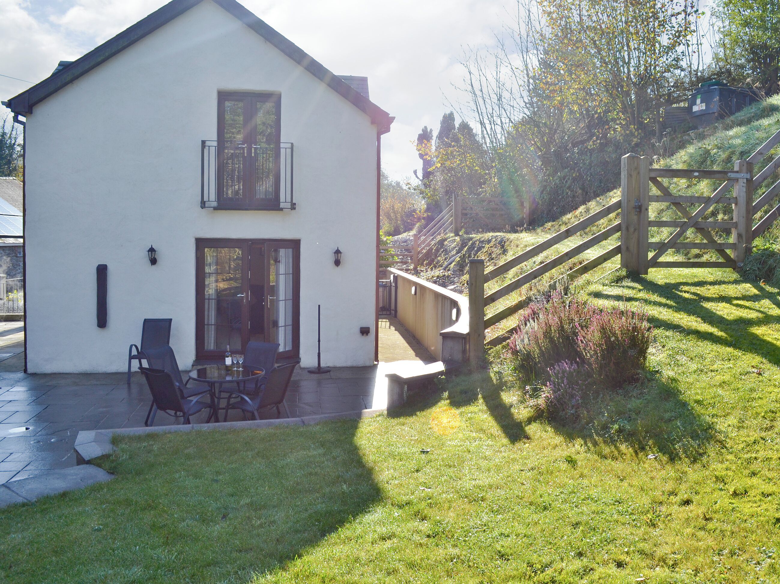 A two-story house with a patio area featuring outdoor seating and a table.