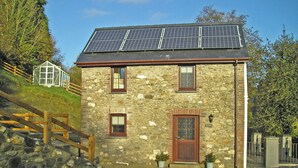 A stone building with a wooden door, windows, and a solar panel roof.