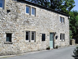 Un bâtiment en pierre doté de nombreuses fenêtres, d’une porte verte et d’une petite enseigne.