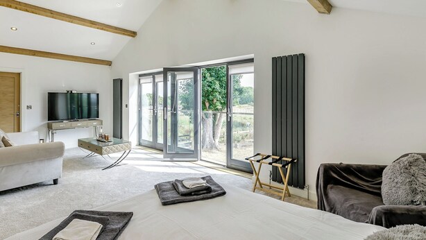 A modern bedroom with a large bed, a TV, and a view of the outdoors. - 6 bedroom accommodation in Howell (Howell)