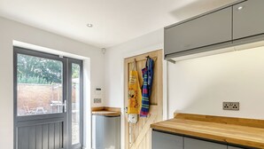 A modern kitchen with grey cabinets, a wooden countertop, and a built-in oven. There is a window with a view of the outside, and a door leading to a patio area. - 6 bedroom accommodation in Howell (Howell)