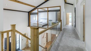 A modern interior with a staircase, a bedroom with a bed and a desk, and a view through a glass door. - 6 bedroom accommodation in Howell (Howell)