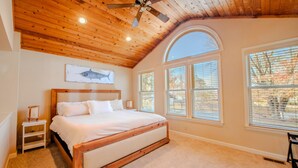 Un dormitorio con techo de madera, una cama, una mesita de noche y una ventana con persianas.