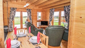 Eine Holzhütte mit Essbereich für vier Personen, einer Couch und einem Fernseher.