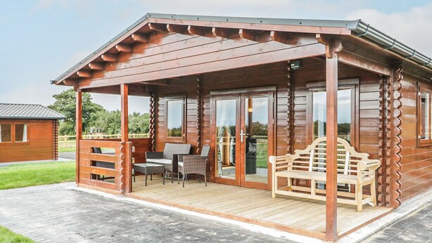 Eine Holzhütte mit überdachter Veranda, Essbereich und Sitzbank.