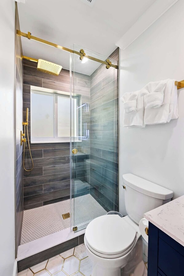 Un bagno moderno con box doccia in vetro, un water bianco e un mobile lavabo con piano in marmo.