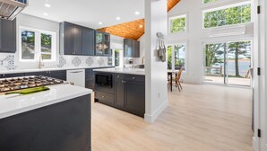 A modern kitchen with dark cabinets, a white countertop, and a wooden ceiling. - Water Front Cottage in Stanley Bridge- Just Minutes To Cavendish Beach (Breadalbane)