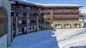 Ein mehrstöckiges Hotel mit Balkonen, steinernen Bögen und einer verschneiten Landschaft.