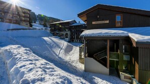 Ein schneebedecktes Skigebiet mit Holzhäusern, darunter eine Lodge namens 'Backgammon'.