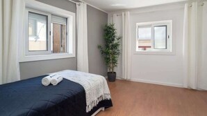 A bedroom with a bed, two windows, a potted plant, and a view of the outside. - Downtown Cosy House by Host Wise (Porto)