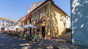 A street with outdoor seating, a building with a sign for a restaurant, and a bus stop. - Downtown Cosy House by Host Wise (Porto)