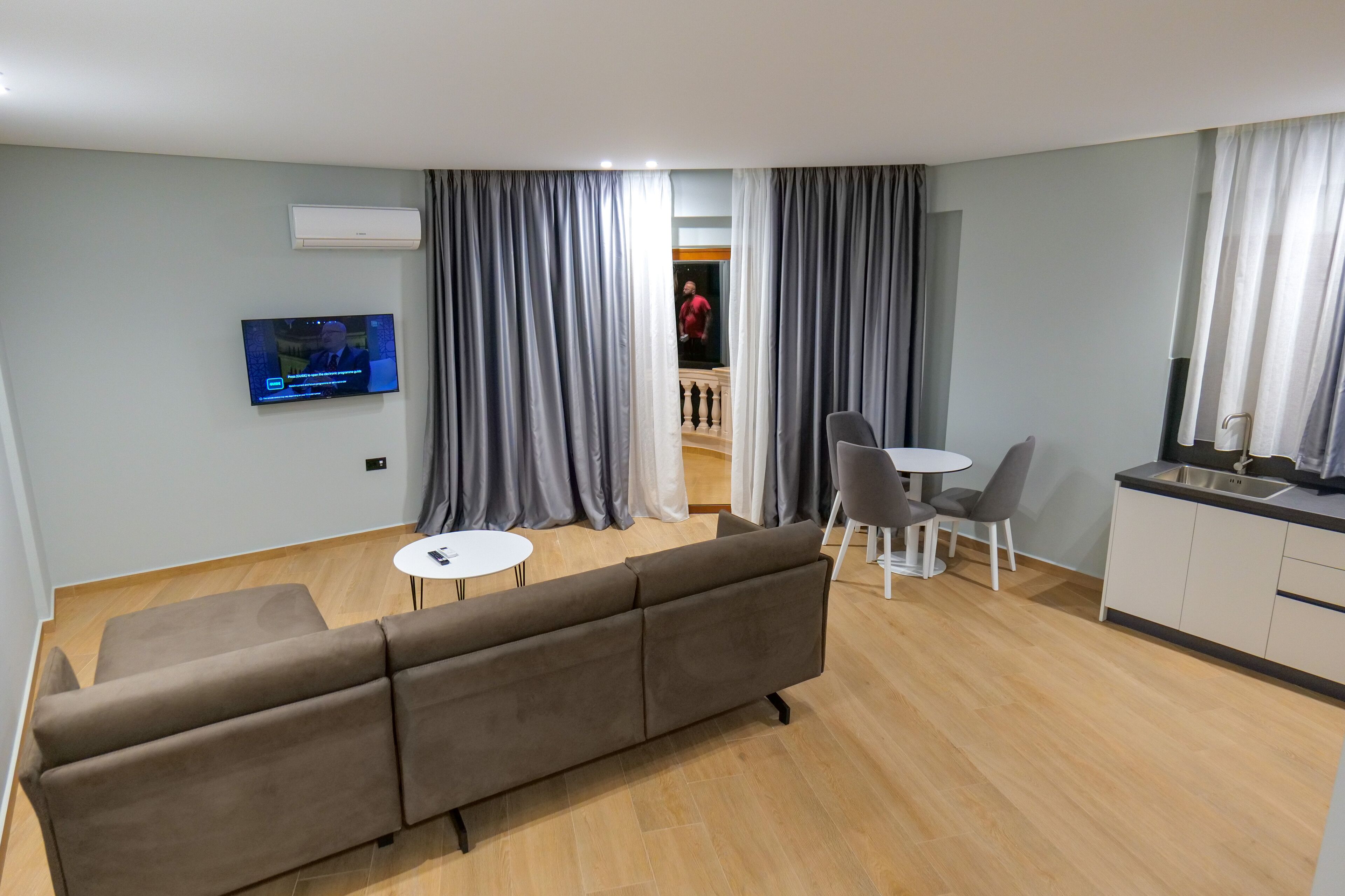 A modern living room with a sofa, a small round table, and a TV mounted on the wall.