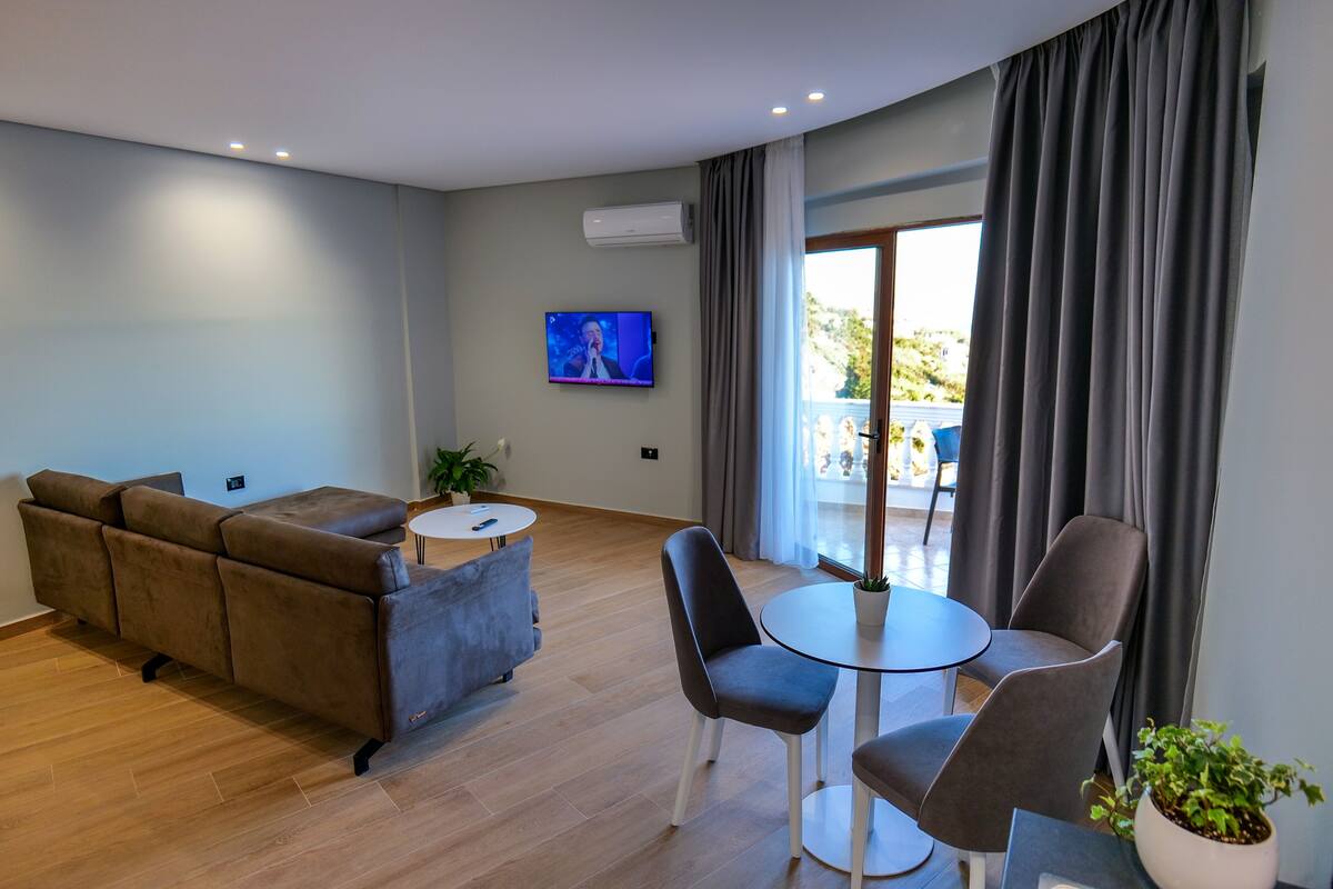 A modern living room with a sofa, chairs, a small table, and a TV.
