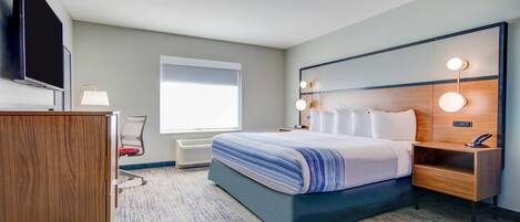 Ein Hotelzimmer mit einem Bett, einem Schreibtisch, einem Sessel, einem Fernseher und einem Fenster.