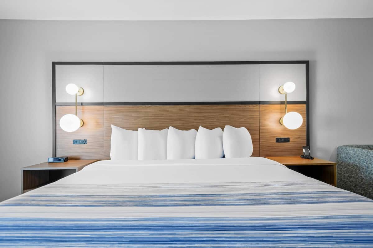 Ein Hotelzimmer mit einem großen Bett, zwei Nachttischen, einem Beistelltisch und einem Kopfteil mit integrierter Beleuchtung.