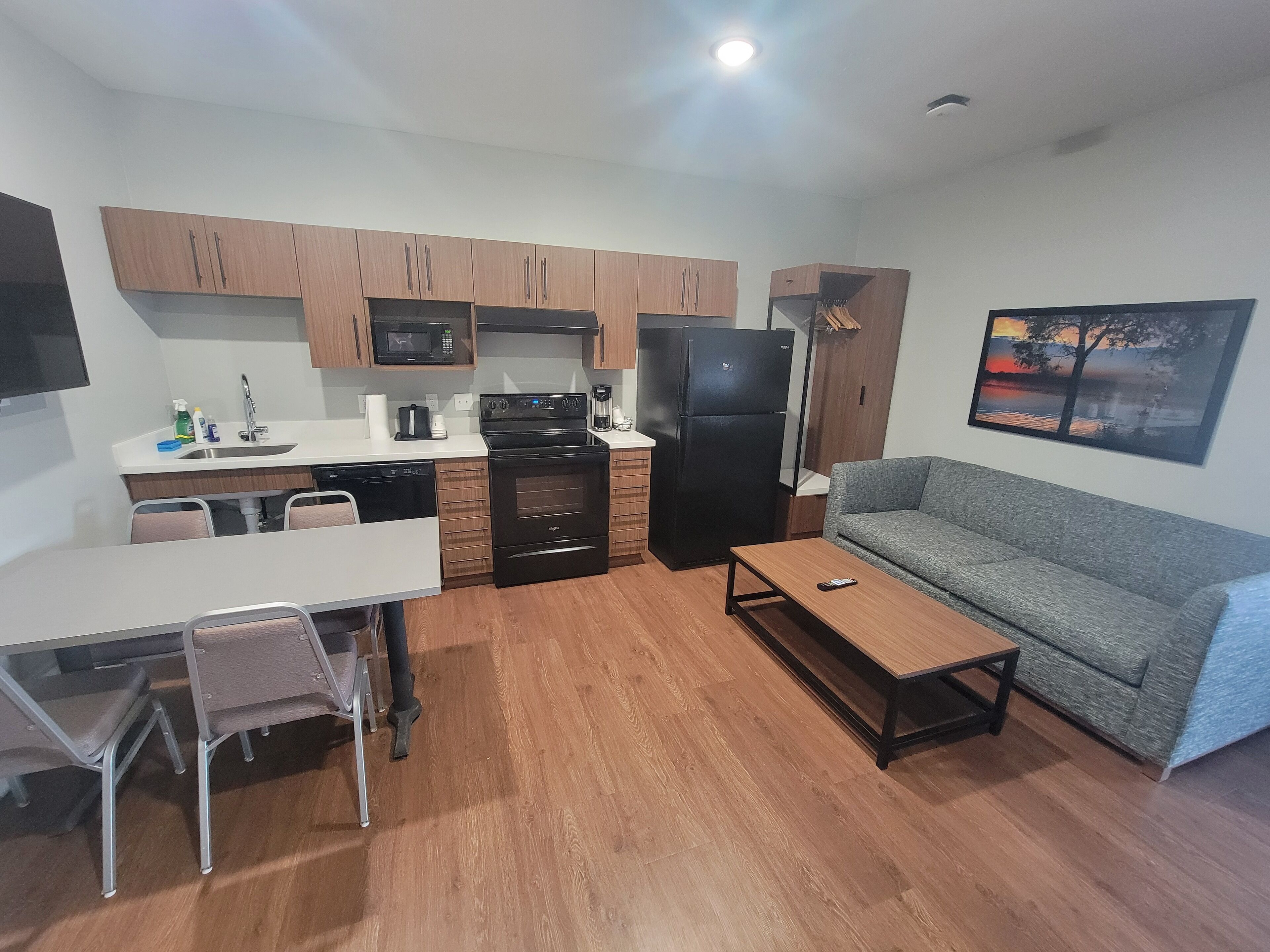 A compact living space with a kitchenette, a dining area, and a seating area with a sofa and a coffee table.