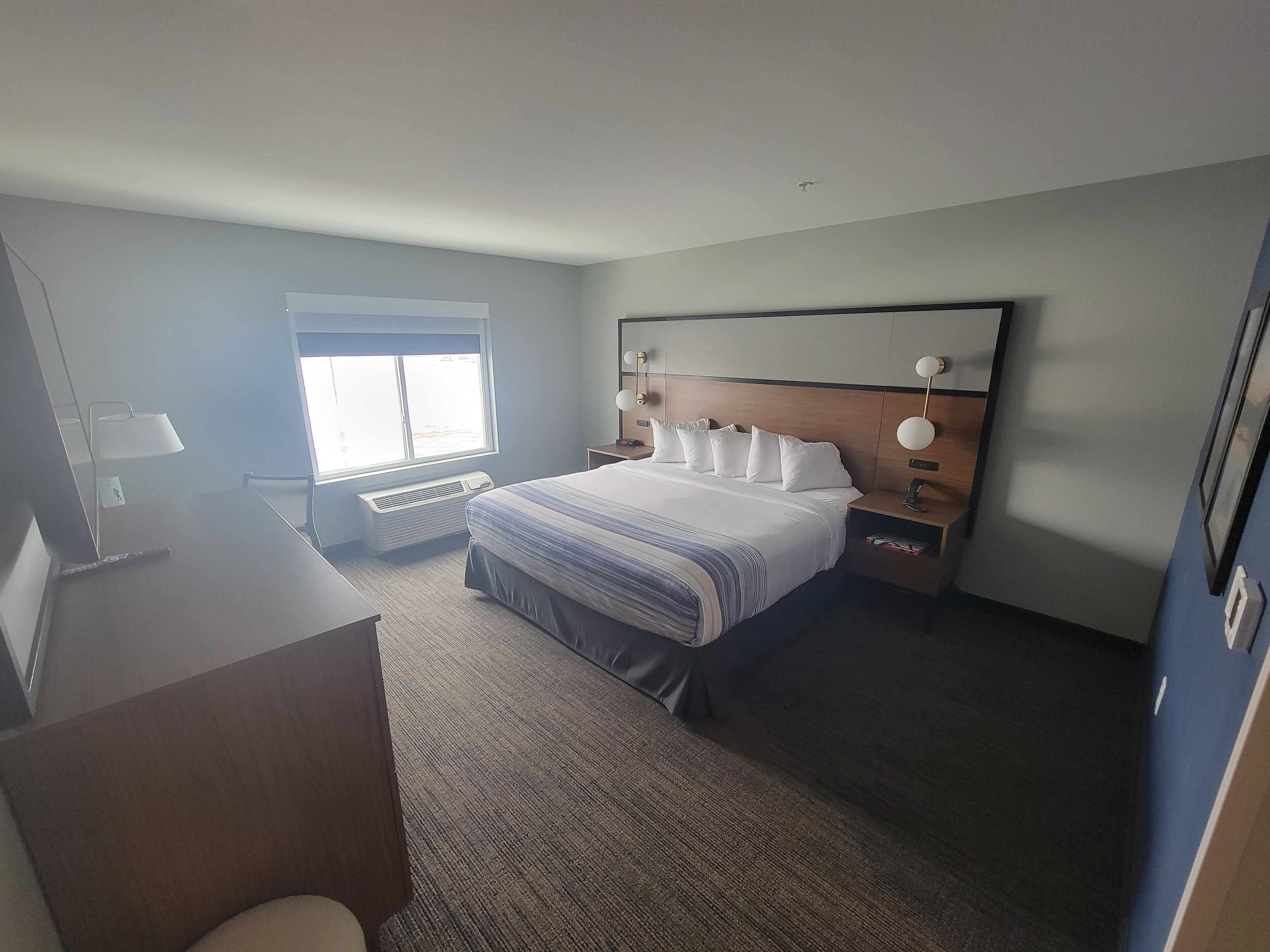 Ein Hotelzimmer mit einem großen Bett, Nachttischen, einem Schreibtisch und einem Fenster.