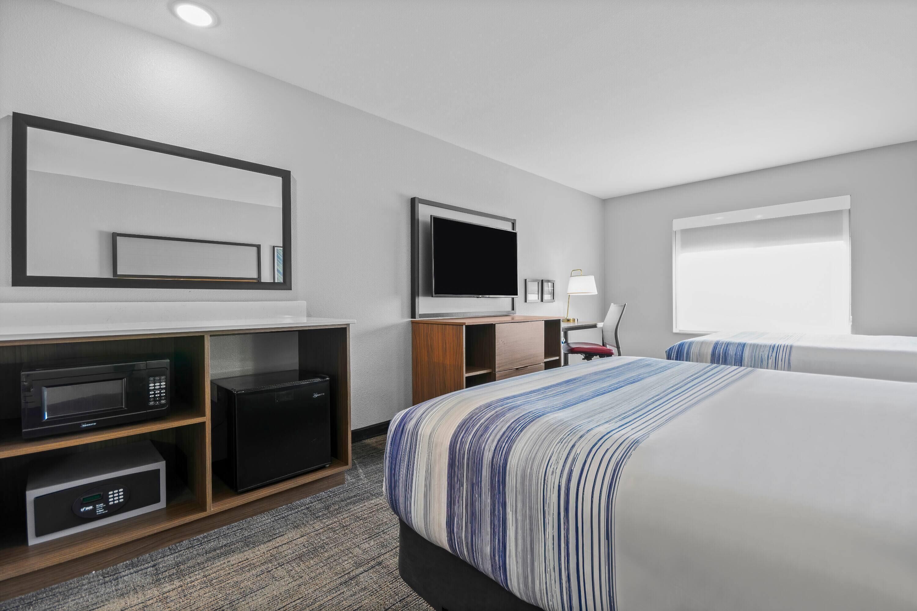 Ein Hotelzimmer mit Bett, Fernseher, Mikrowelle und kleinem Kühlschrank.