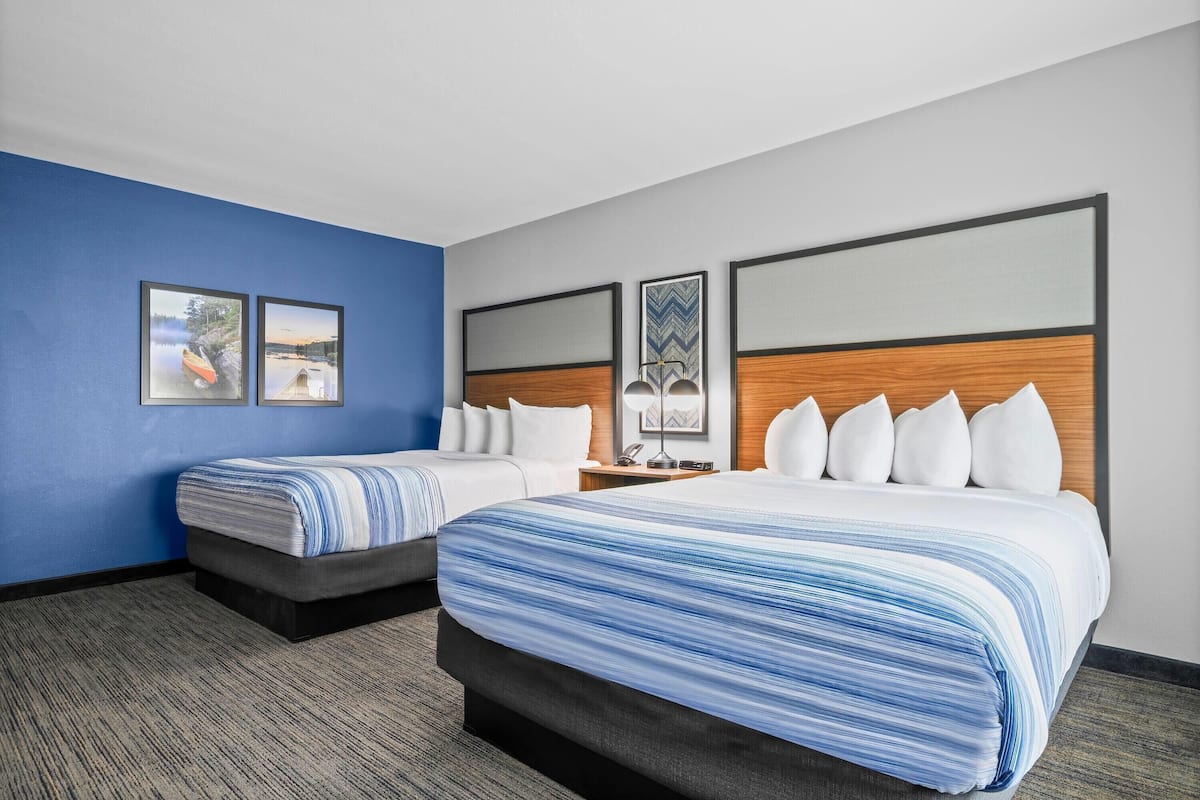 Ein Hotelzimmer mit zwei Betten, einer blauen Akzentwand und gerahmten Bildern an der Wand.