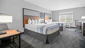 Quarto de hotel com uma cama grande, uma escrivaninha, uma cadeira e uma janela.