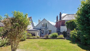 Una casa residencial con patio delantero, un pequeño jardín y un cielo azul despejado.