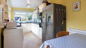 Cocina compacta con lavadora, refrigerador y comedor con mantel estampado de lunares.
