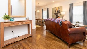 Una sala de estar moderna con una consola de madera, un sofá de cuero y un comedor al fondo.