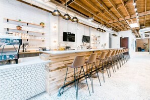 A modern bar area with a long counter, multiple stools, and a white hexagonal tile backsplash. - Stylish 2BR in Villa Heights, Steps from Greenway, Near NoDa & Uptown (Charlotte)