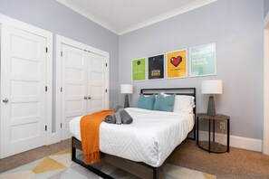 A bedroom with a bed, two bedside tables, a nightstand, a wall-mounted lamp, and four framed motivational posters. - Stylish 2BR in Villa Heights, Steps from Greenway, Near NoDa & Uptown (Charlotte)