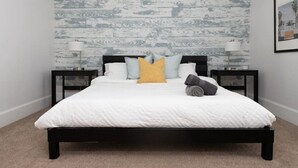 Un dormitorio con cama, dos mesitas de noche y una pared con textura decorativa.