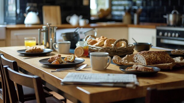 A breakfast table with croissants, bread, a coffee cup, and a glass of orange juice. - 3 bedroom accommodation in Clynnog Fawr (Clynnog Fawr)