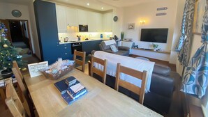 A modern living space with a dining area, kitchen, and a TV.