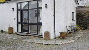 Un edificio blanco con amplios ventanales y una puerta, un sendero de grava y dos plantas en macetas.