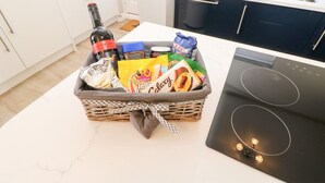 A kitchen with a basket of snacks, a bottle of wine, and a toaster. - Lobster Pot Retreat (Newbiggin-by-the-Sea)
