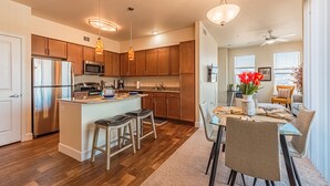 Une cuisine moderne avec des meubles en bois, des appareils électroménagers en acier inoxydable et un îlot central doté de tabourets.