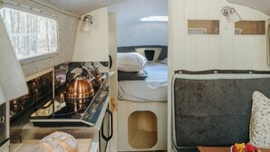 Een kleine keuken met een fornuis, waterkoker en een brood op een snijplank.