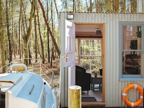 A small cabin with a door leading to an interior that includes a sofa, a small table, and a window.