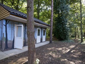 Une rangée de cabanes au toit en bois, entourées d’arbres, dans un cadre forestier.