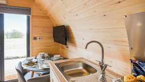 Una cocina compacta con paredes de madera, un lavamanos moderno y una zona de comedor con una mesa y sillas.